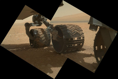 Three of Curiositys wheels rolling through the dirt...on Mars! The base of Mt. Sharp is in the distance. Image credit: NASA/JPL/Malin Space Science Systems.